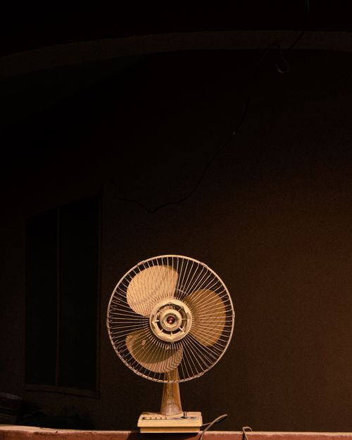 Free A vintage electric fan sits in a dimly lit indoor setting, evoking a warm, nostalgic atmosphere. Stock Photo