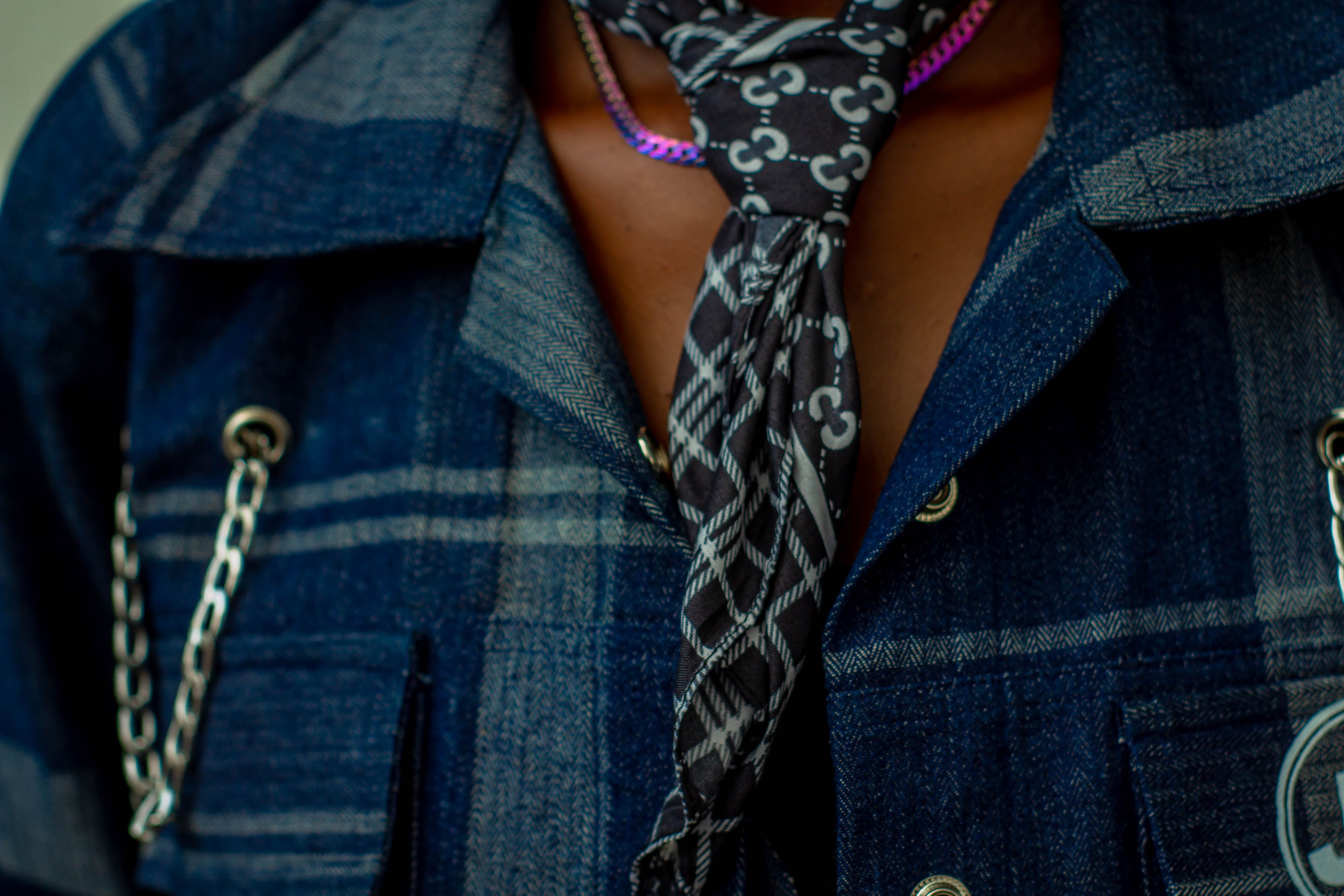 A detailed view of a plaid denim jacket paired with a patterned necktie.