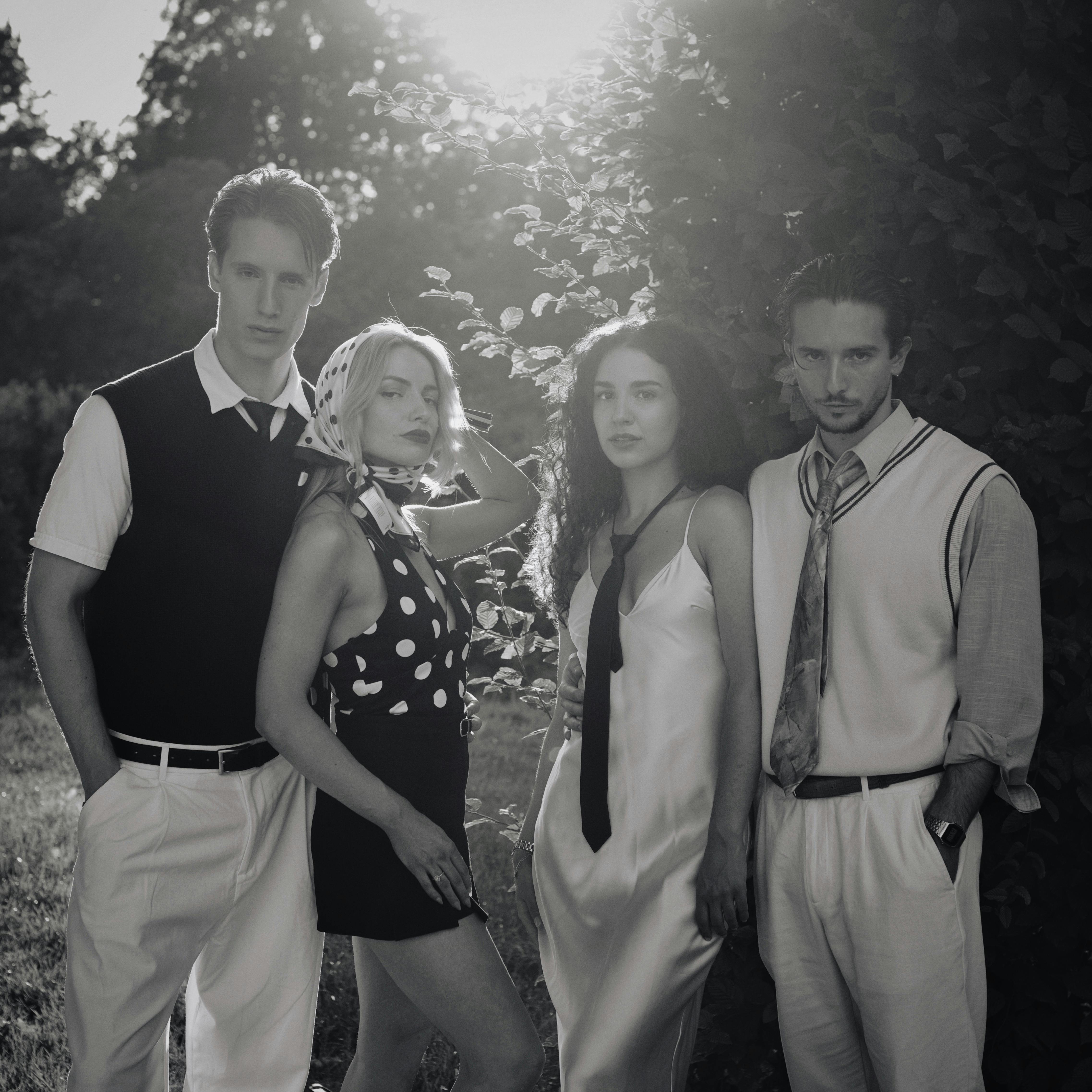 Gratis Ritratto di gruppo in bianco e nero che cattura la moda retrò con retroilluminazione naturale. Foto a disposizione