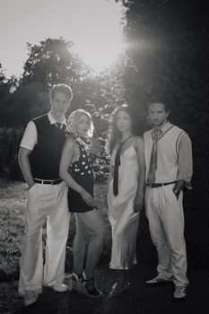 Black and white photo of four adults in vintage attire posing outdoors at sunset. - Fotografer Sidoarjo