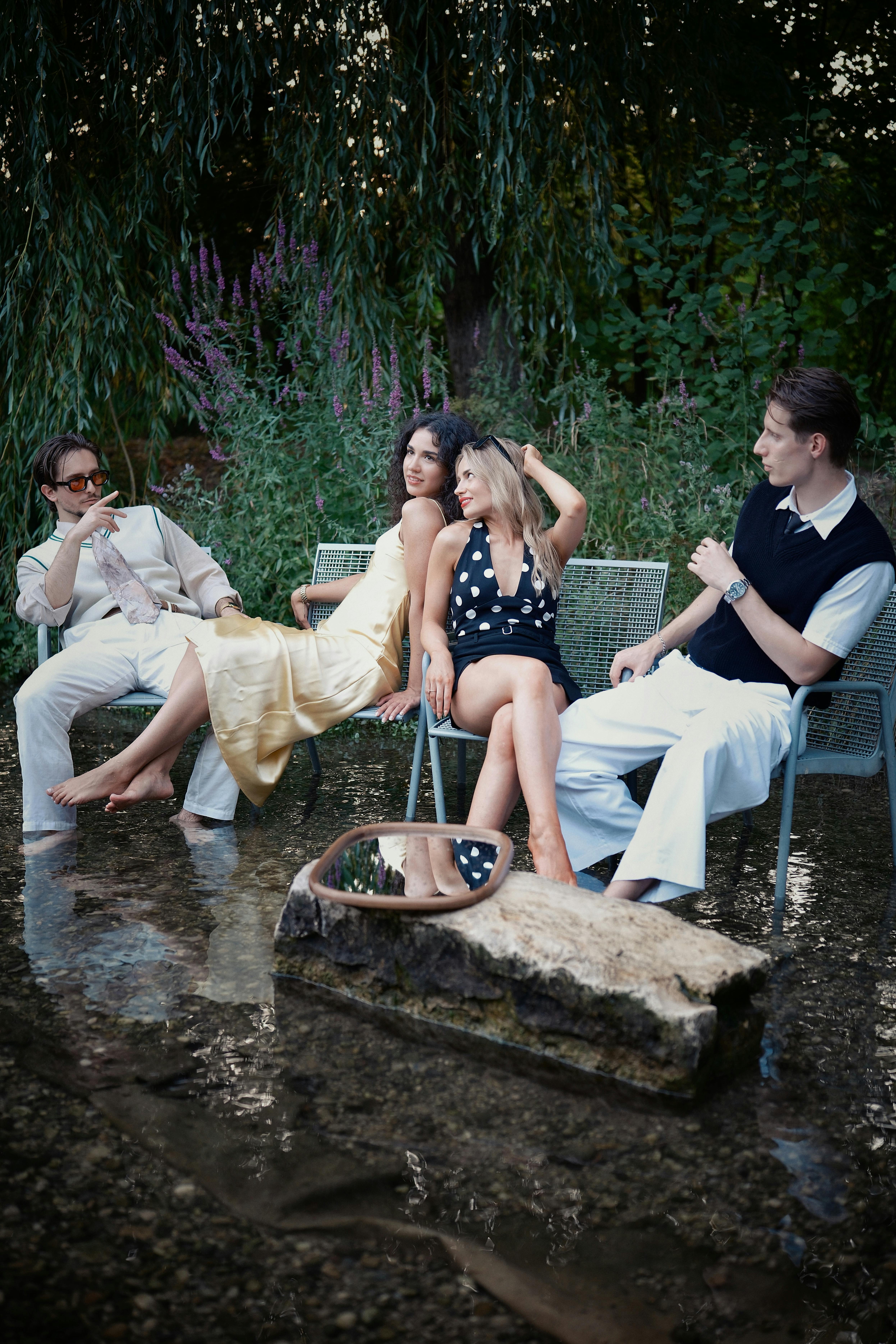 A stylish group relaxing by a stream, blending fashion and nature during the day.