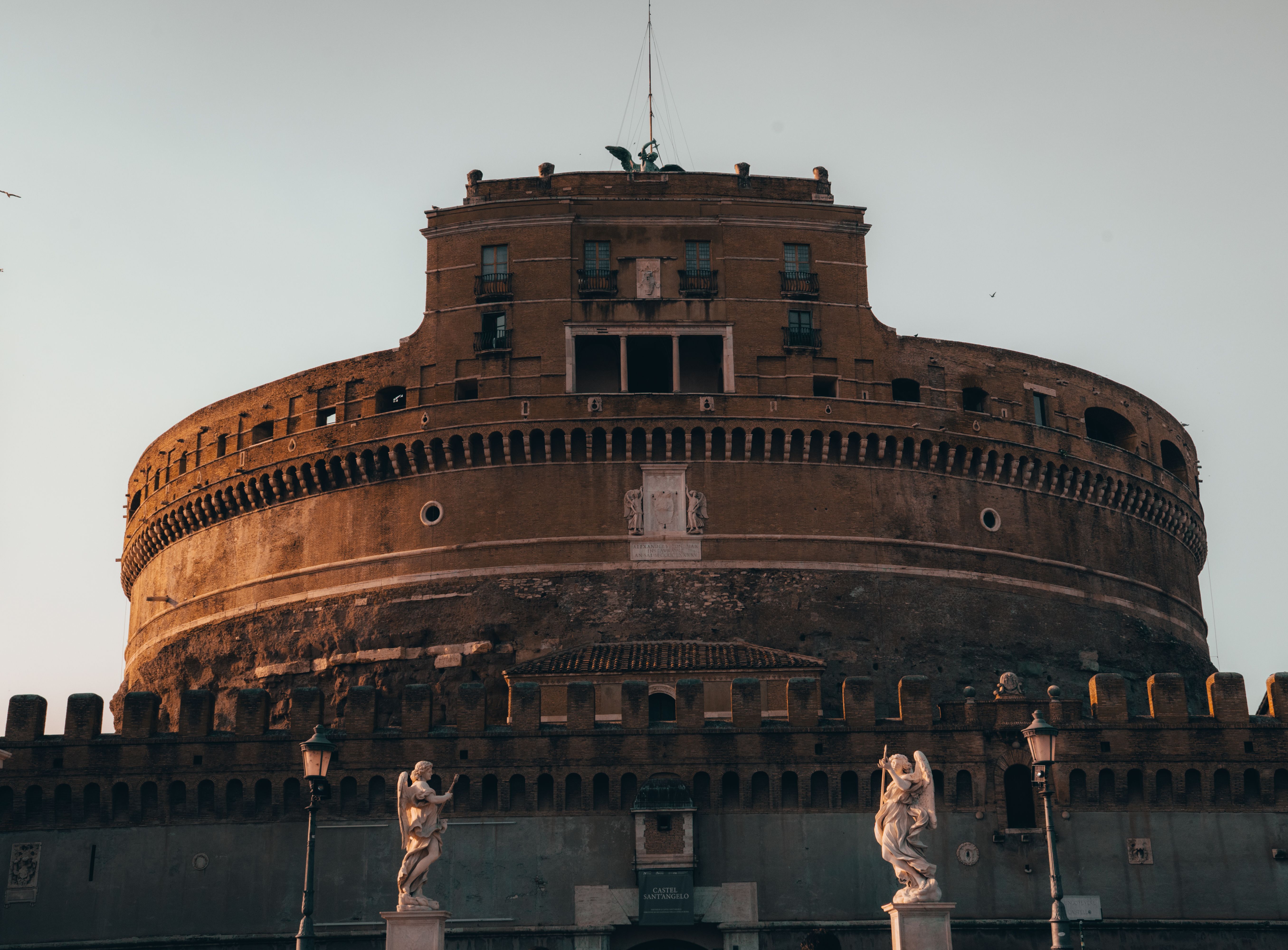 View of the historic Castel Sant'Angelo with angel statues at sunset in Rome, Italy, epitomizing ancient architecture.
