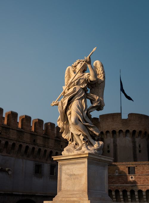 Free A majestic angel statue holding a spear stands at Castel Sant'Angelo in Rome under a clear sky. Stock Photo