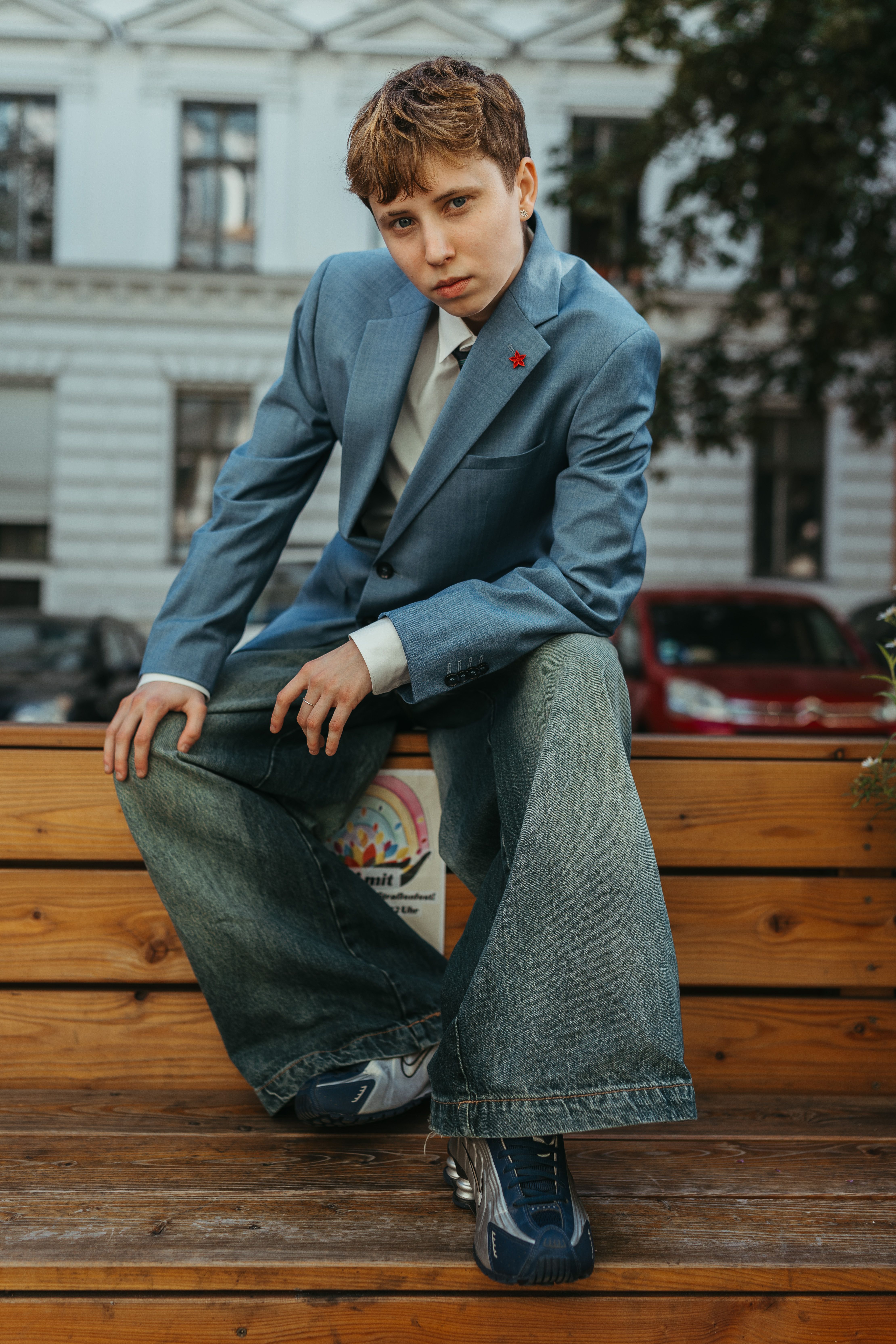 Stylish individual posing in urban Berlin, showcasing modern fashion with wide-leg jeans and a blue blazer.