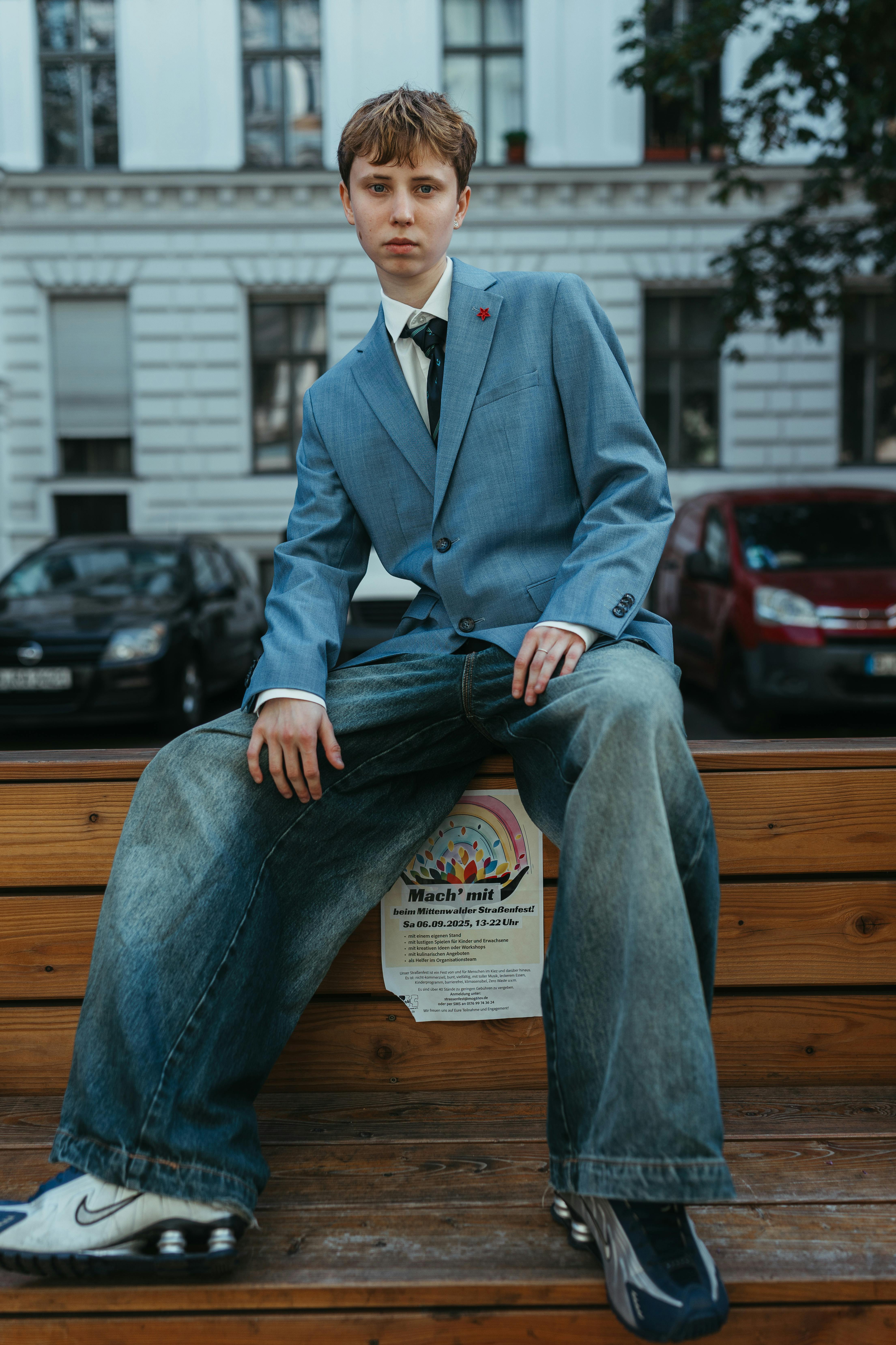 Fashionable young adult posing outdoors in Berlin wearing wide-leg jeans and a blue blazer.