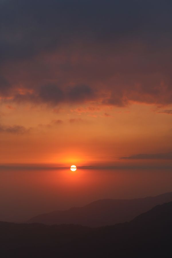 Um pôr do sol tranquilo sobre as montanhas do Nepal com cores vibrantes do céu.