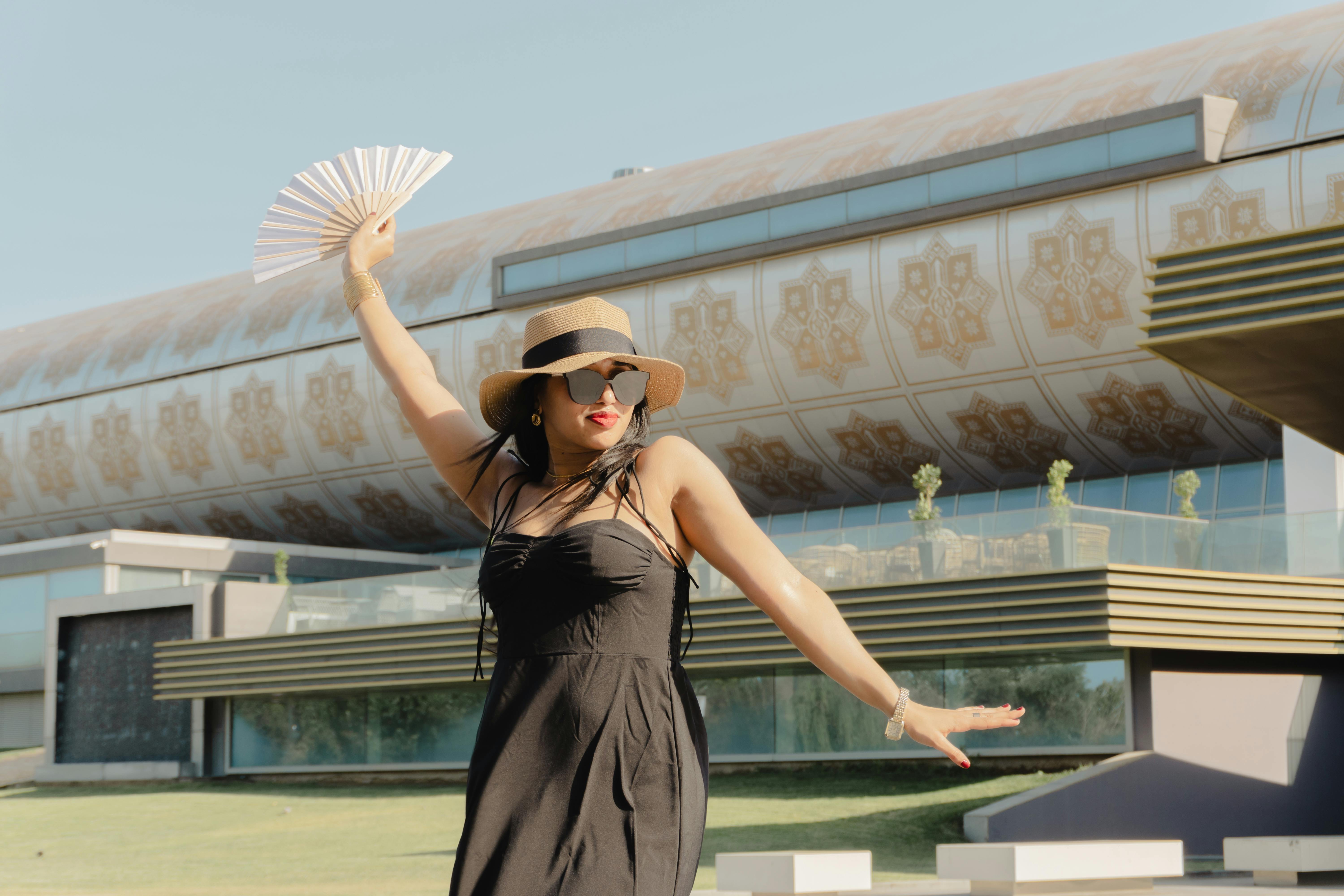 Stylish woman in Baku, Azerbaijan holding a fan, embracing a sunny day.