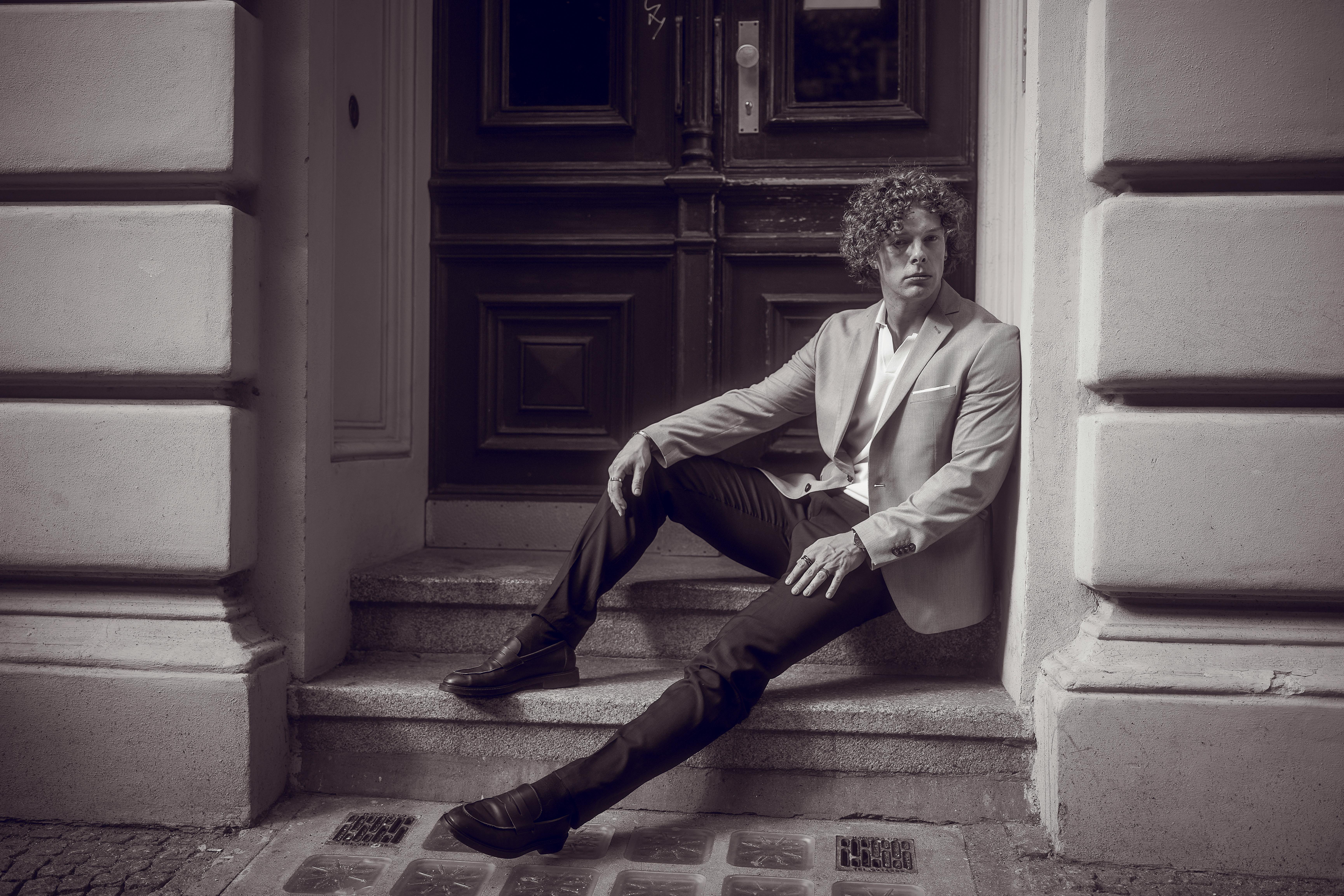 Free Black and white portrait of a stylish man seated on a doorstep in Berlin. Stock Photo