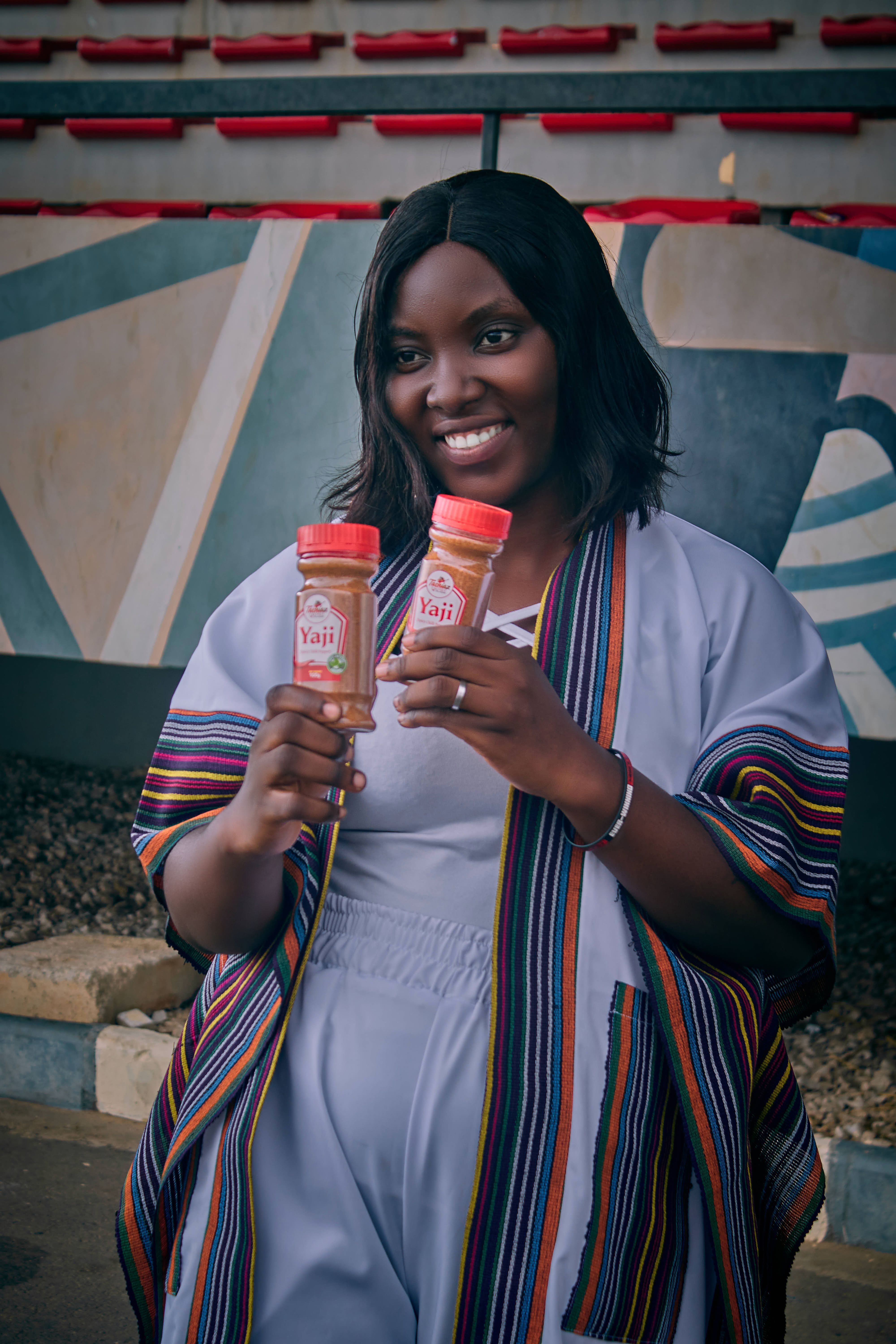 Cheerful woman in traditional attire showcasing seasoning jars. Perfect for culinary themes.