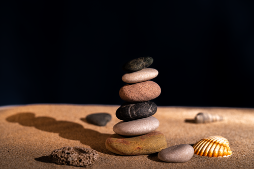 Free Artistic stack of smooth pebbles on sandy beach with seashells, capturing balance and zen. Stock Photo