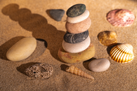 Balanced pebbles and seashells on the sand create a serene scene on a Valencian beach.