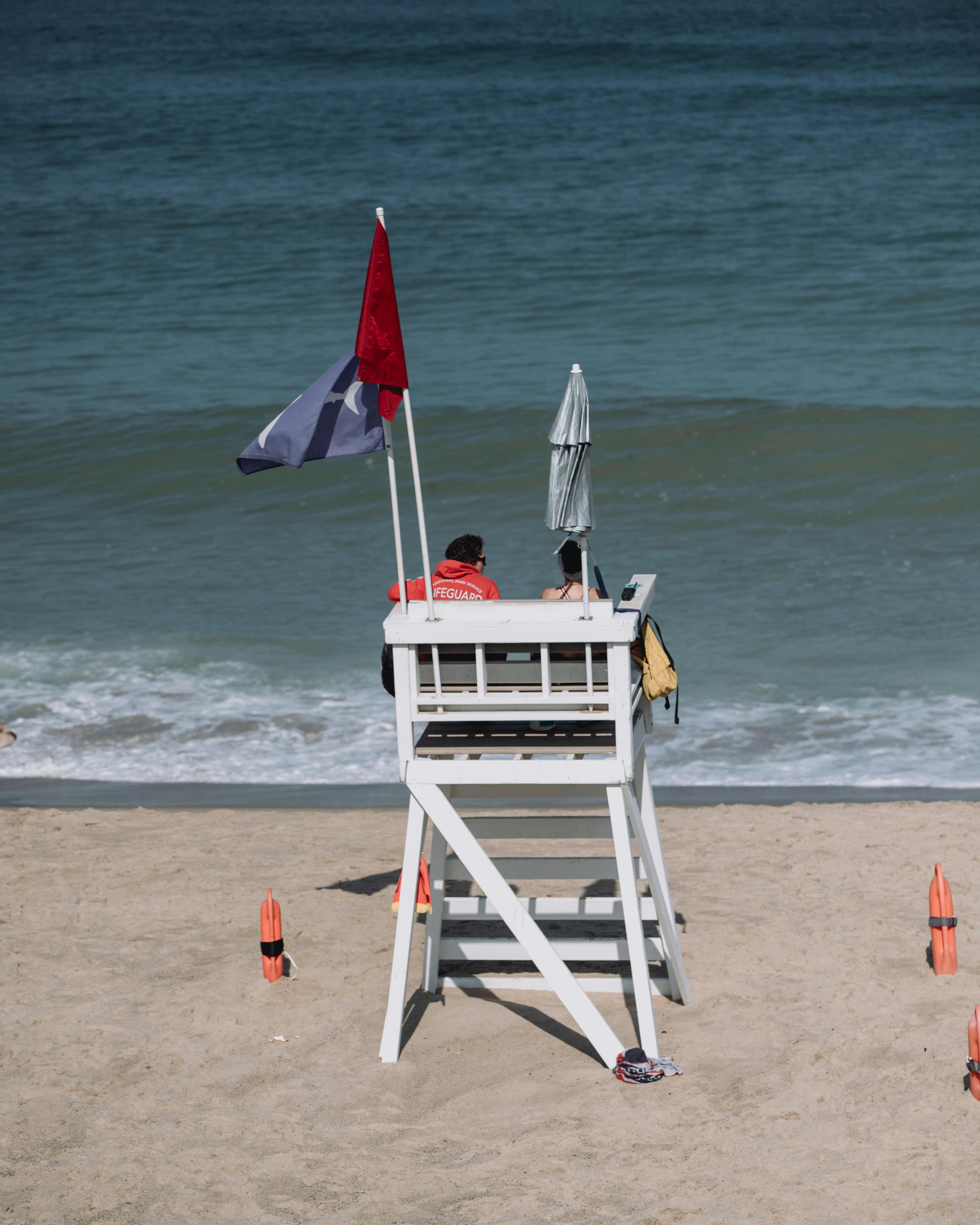 Lifeguard on a wooden tower overseeing a Massachusetts beach, ensuring safety.