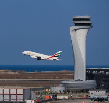 Emirates Airbus A380 taking off at Istanbul Airport with the control tower in view.
