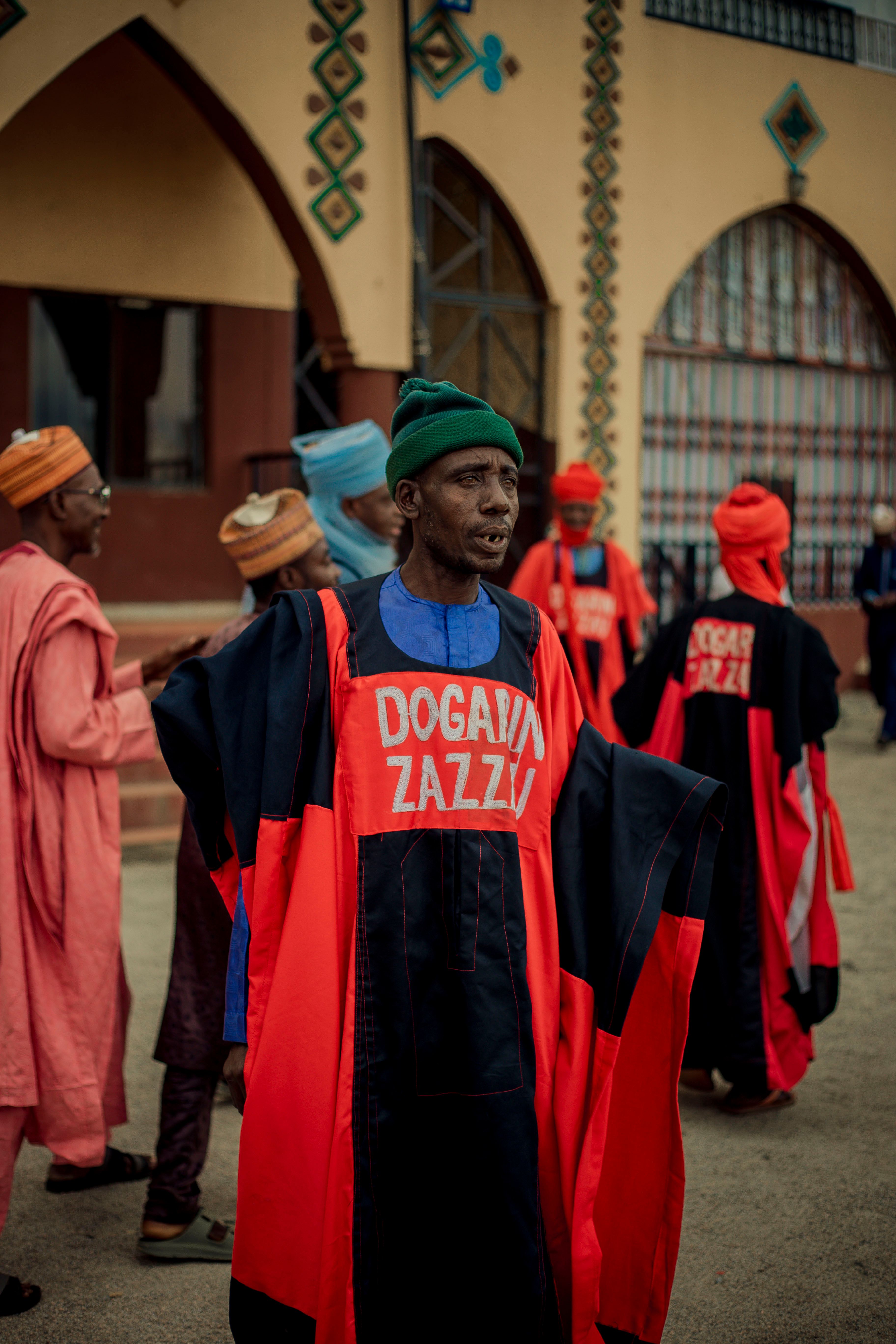 Men in colorful traditional attire outside an ornate building.
