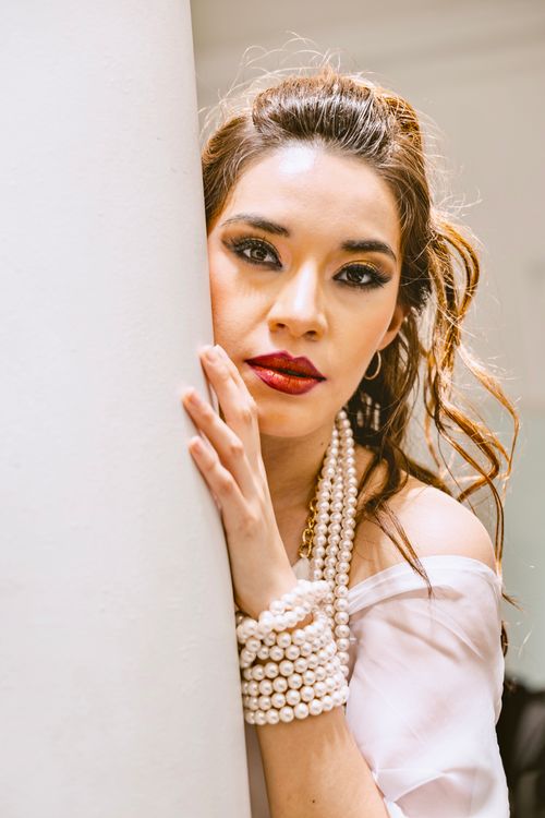 Free Sophisticated woman with pearl accessories and elegant makeup in a modern setting. Stock Photo