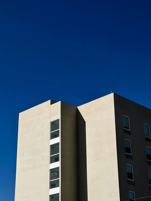 Free A minimalist photo of a modern building with clear blue sky, captured in bright daylight. Stock Photo
