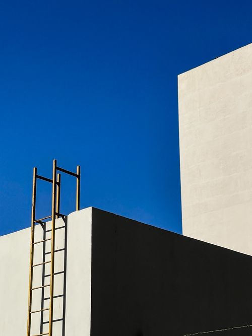 Free Minimalist architectural scene with ladder, geometric shapes, and blue sky. Stock Photo
