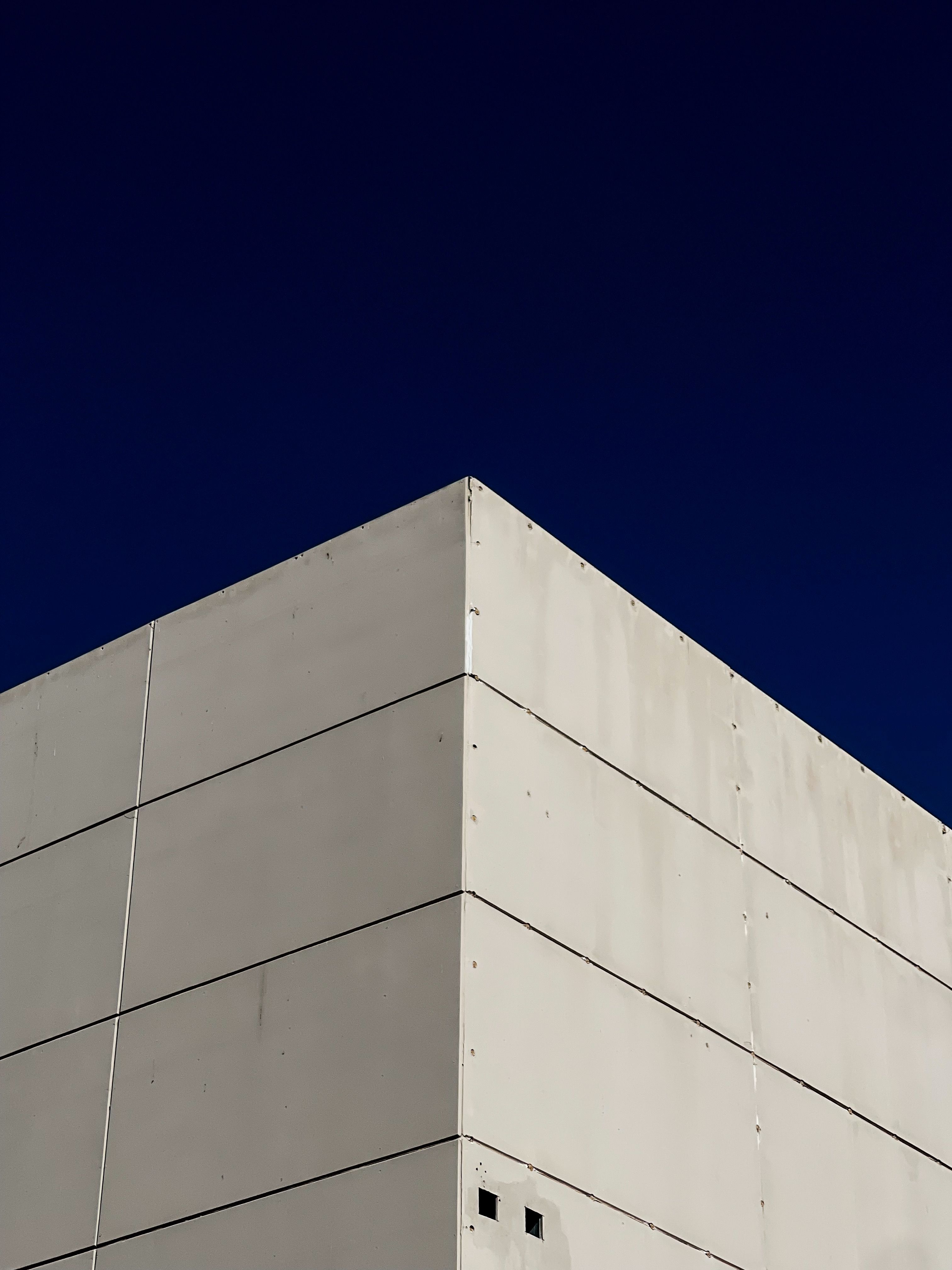 Sharp corner of a concrete building contrasting with a deep blue sky, showcasing modern minimalism.