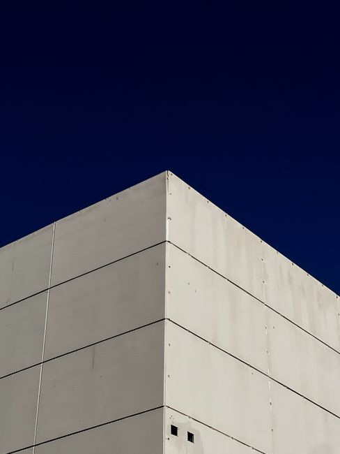 Sharp corner of a concrete building contrasting with a deep blue sky, showcasing modern minimalism.