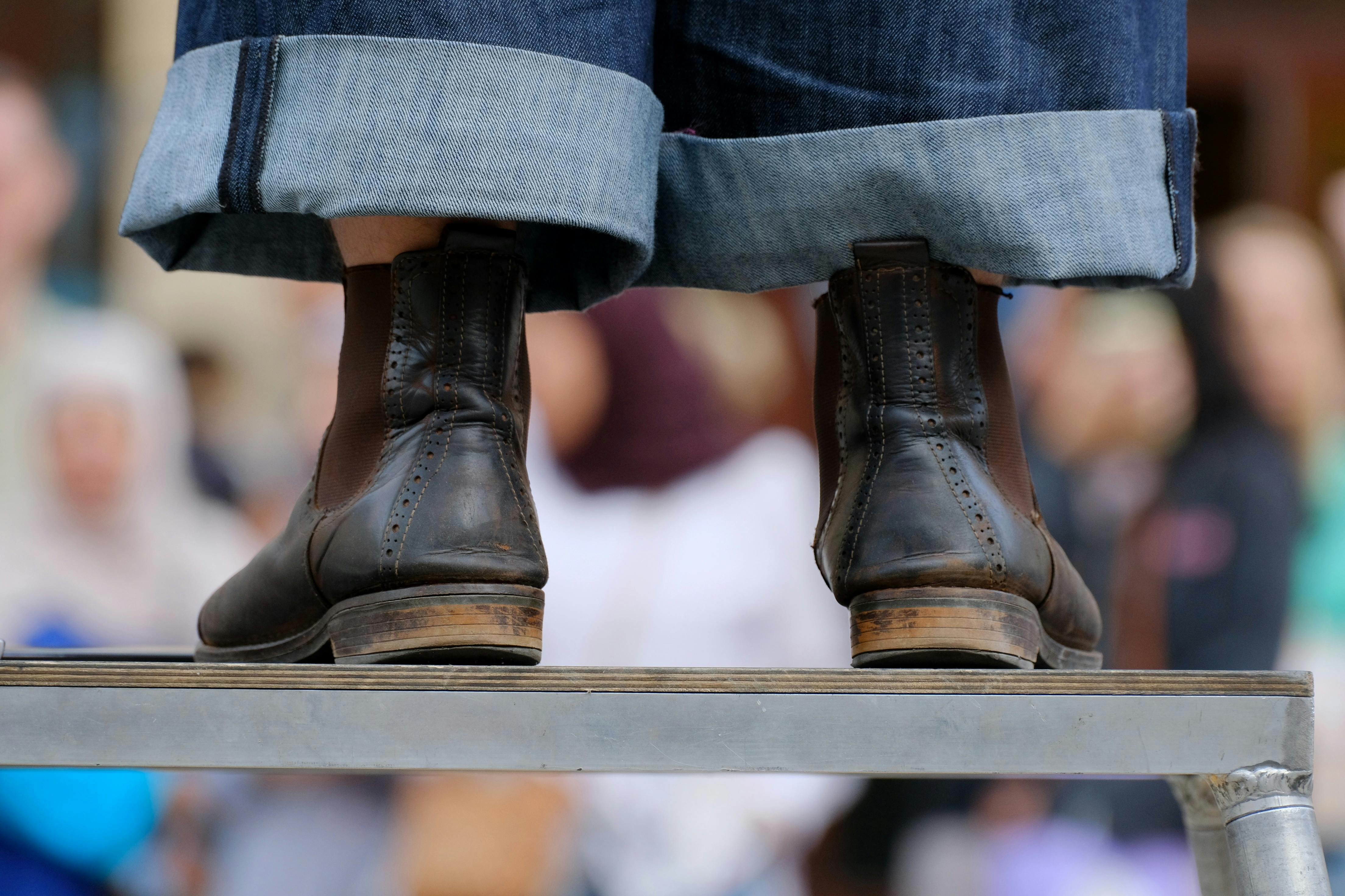 Detailed shot of leather boots and rolled jeans, capturing street fashion style.