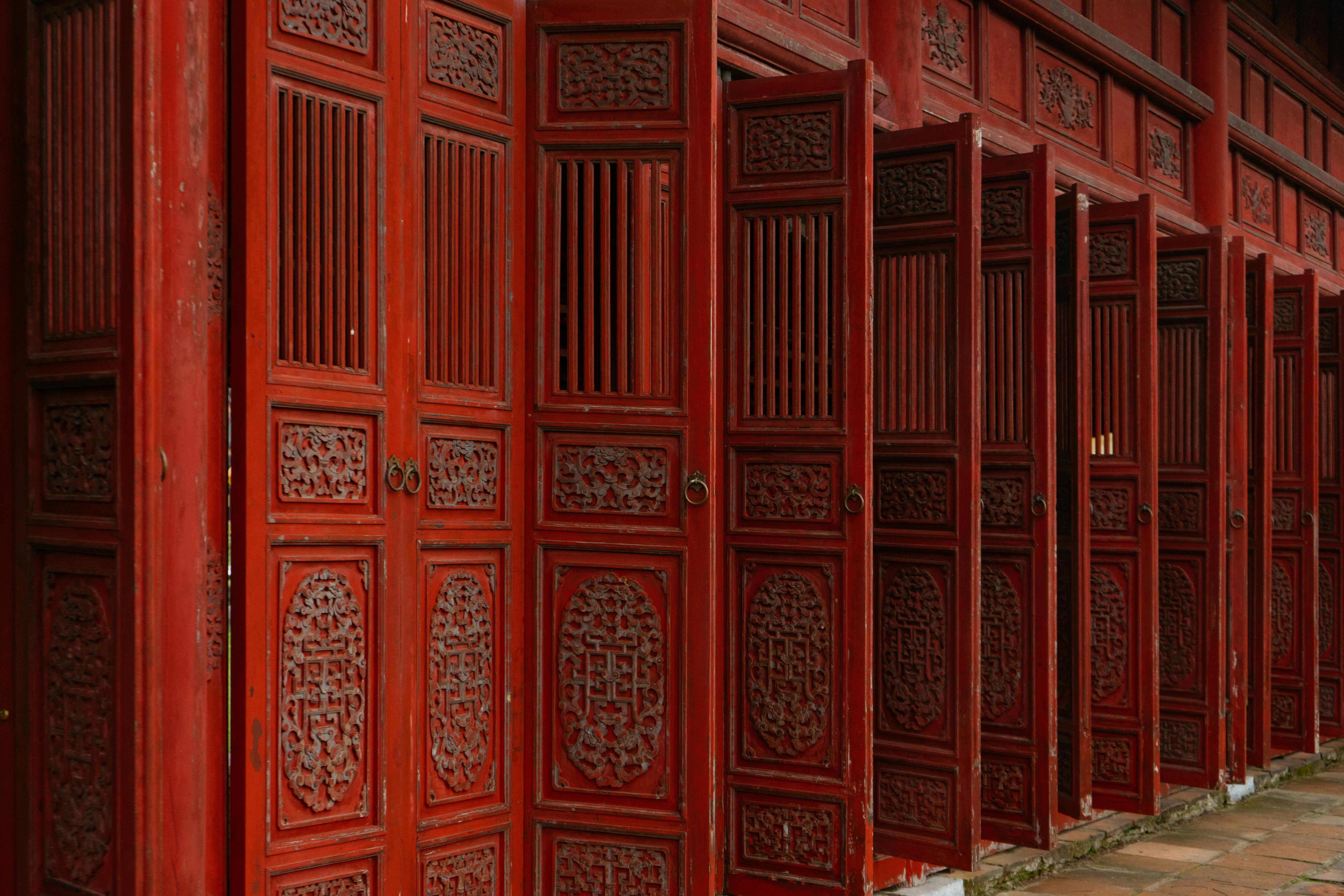 Detailed shot of traditional carved wooden doors in Hue, Vietnam, showcasing cultural heritage.