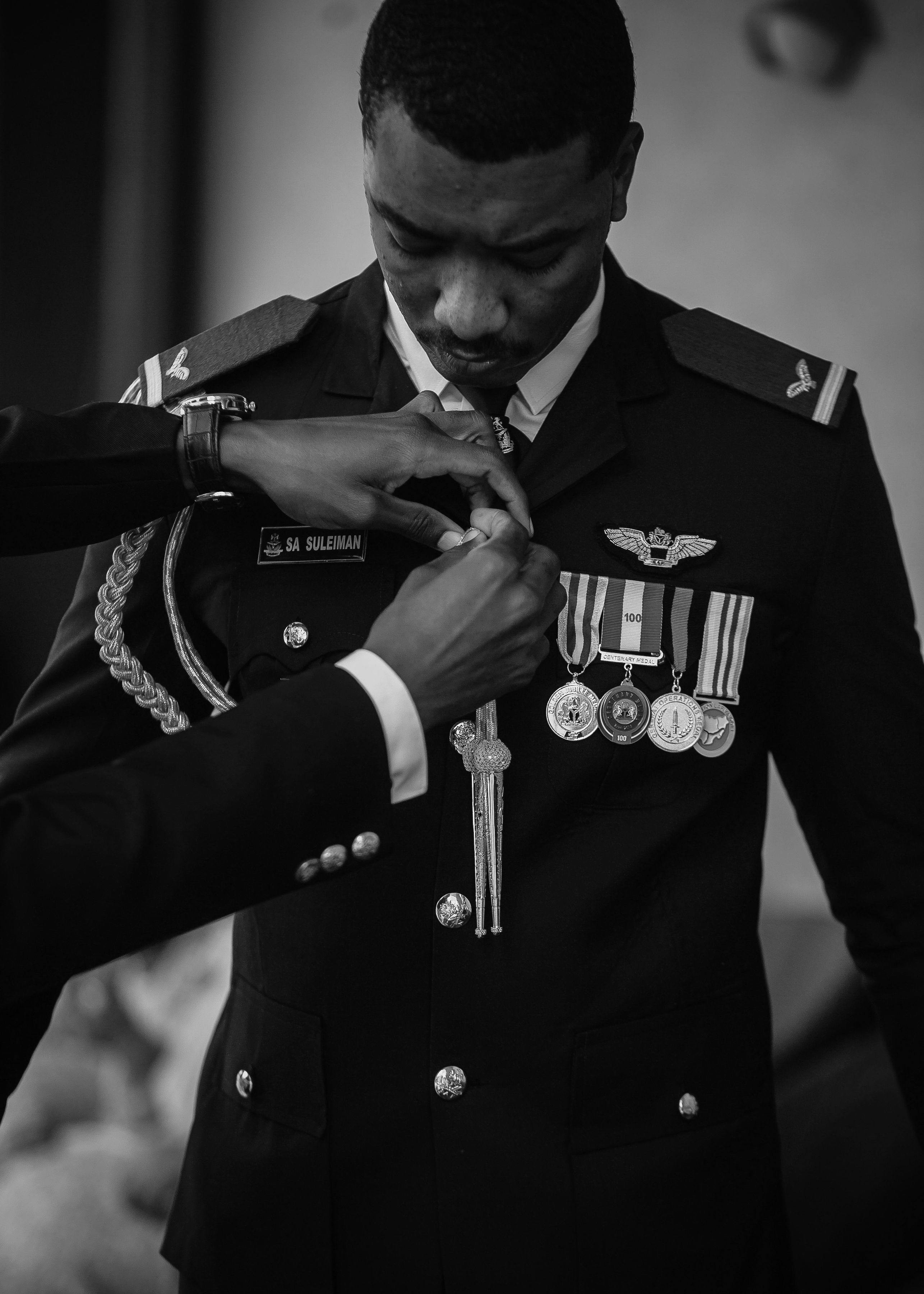 A military officer in uniform receives medals during a formal ceremony. Black and white photo.