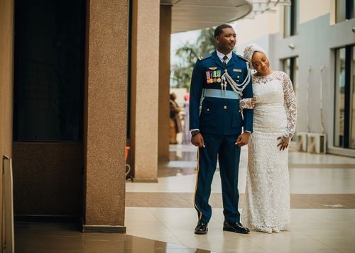Free A couple in elegant wedding attire, bride leaning on groom in uniform. Stock Photo
