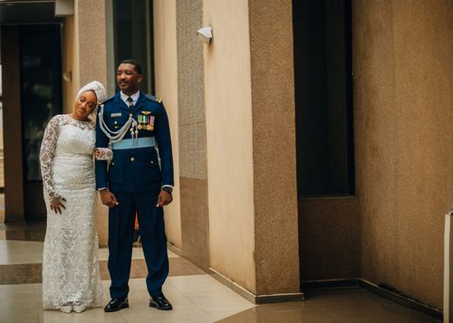 Free A couple beautifully dressed in wedding and military formal attire, standing together indoors. Stock Photo