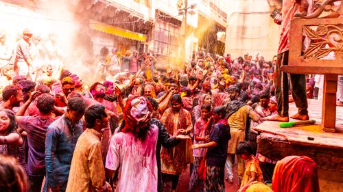 Free Lively street scene of people joyfully celebrating Holi with colors in India. Stock Photo