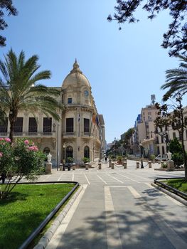 Beautiful government building in a sunlit plaza with palm trees.