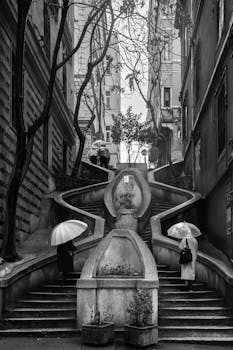 Monochrome photo of umbrella users on famous Istanbul staircase, Türkiye.