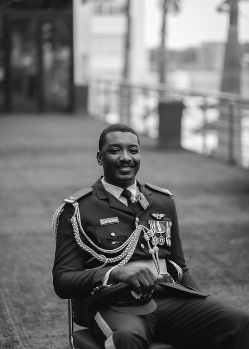 Free Black and white portrait of a smiling military officer in uniform with medals, seated outdoors. Stock Photo