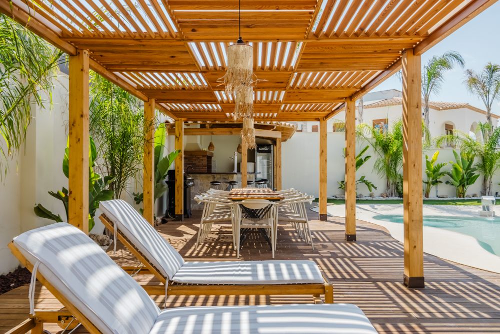 Modern patio with a wooden pergola beside a swimming pool
