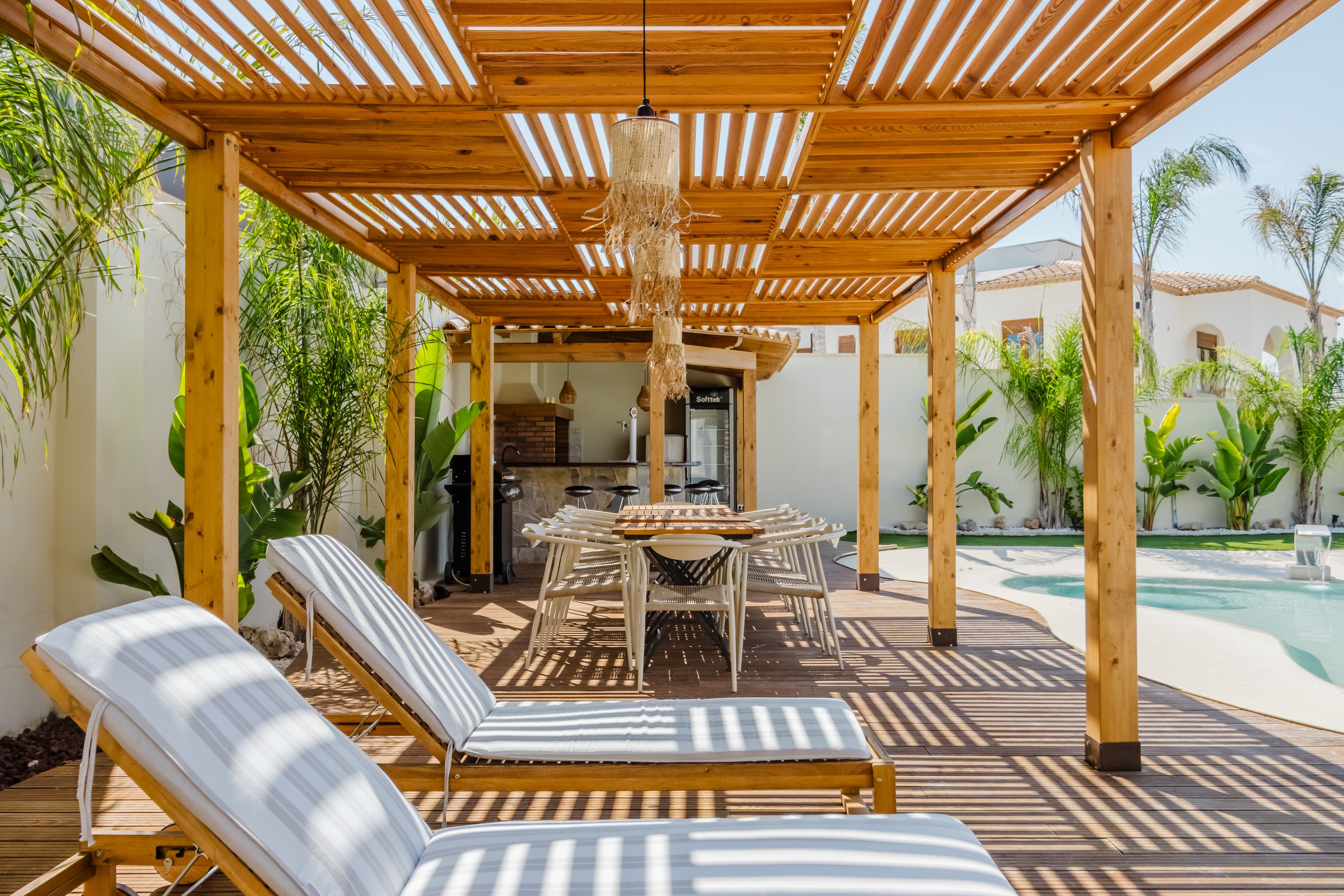 Tropical patio with a pergola, poolside seating, and layered greenery that reflects stylish shaded outdoor living in South Florida.