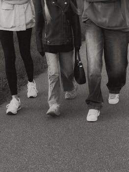 A group of people walking together on a pathway, dressed casually, in a monochrome setting.