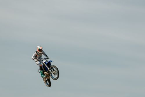 Free A motocross rider performs a high-flying jump against a clear sky during a race. Stock Photo