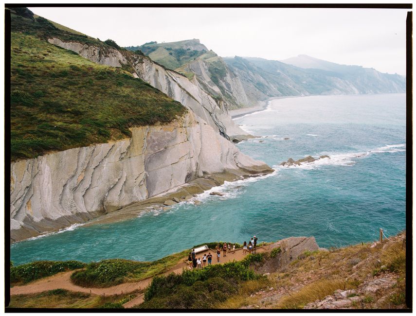 A picturesque view of rugged cliffs meeting the sea, with people enjoying the scenic landscape.