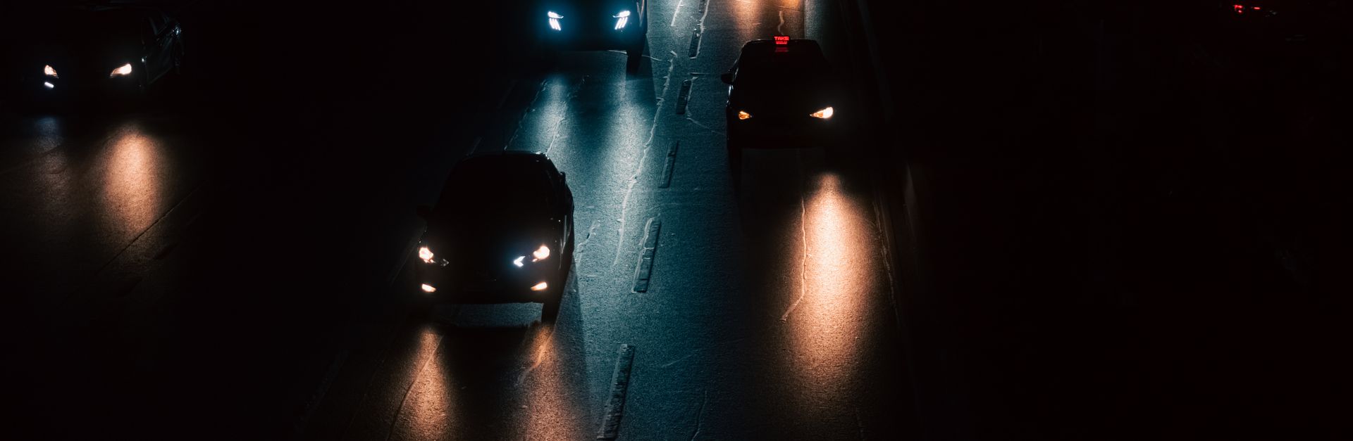 Moody shot of cars driving on an Istanbul street at night with striking headlights.