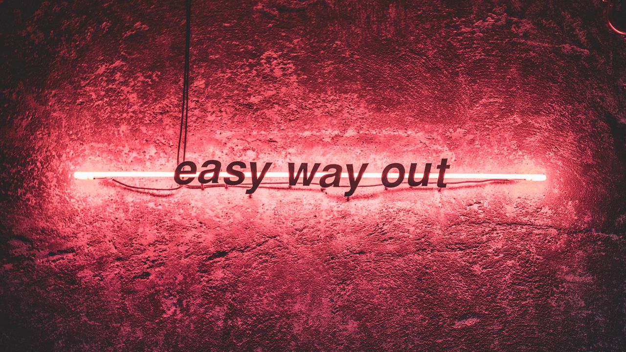 pink neon sign reading easy way out against a textured wall conveying