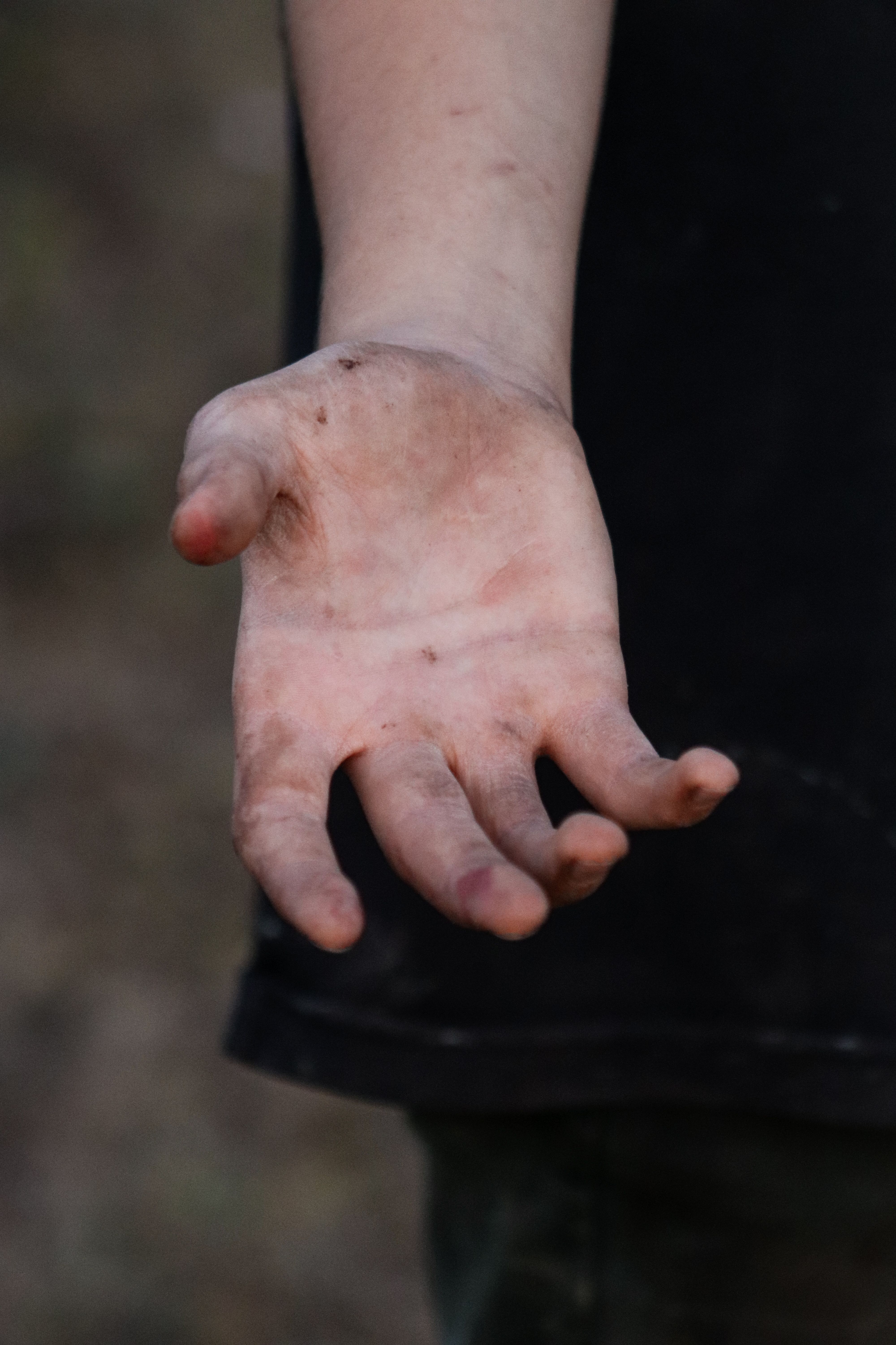 Close-up of a dirty hand showing the palm outdoors, capturing a gritty and natural moment.