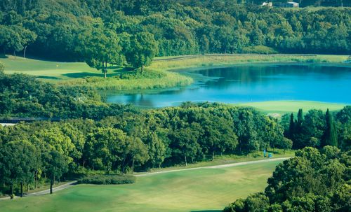 Free Aerial view of a lush green golf course surrounded by forest and a tranquil lake. Stock Photo