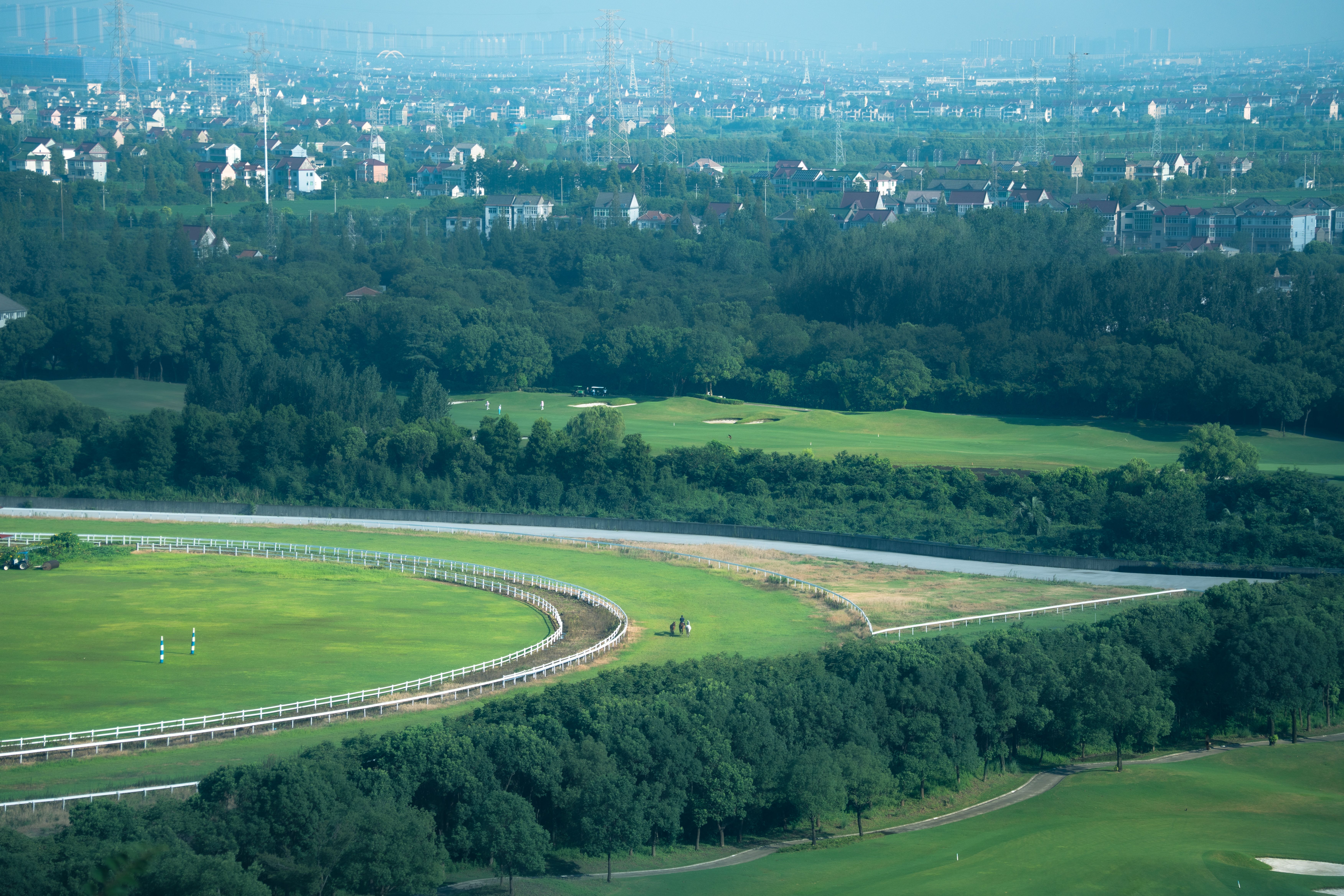 英國賽馬場晨霧籠罩草地跑道，騎師帶馬熱身