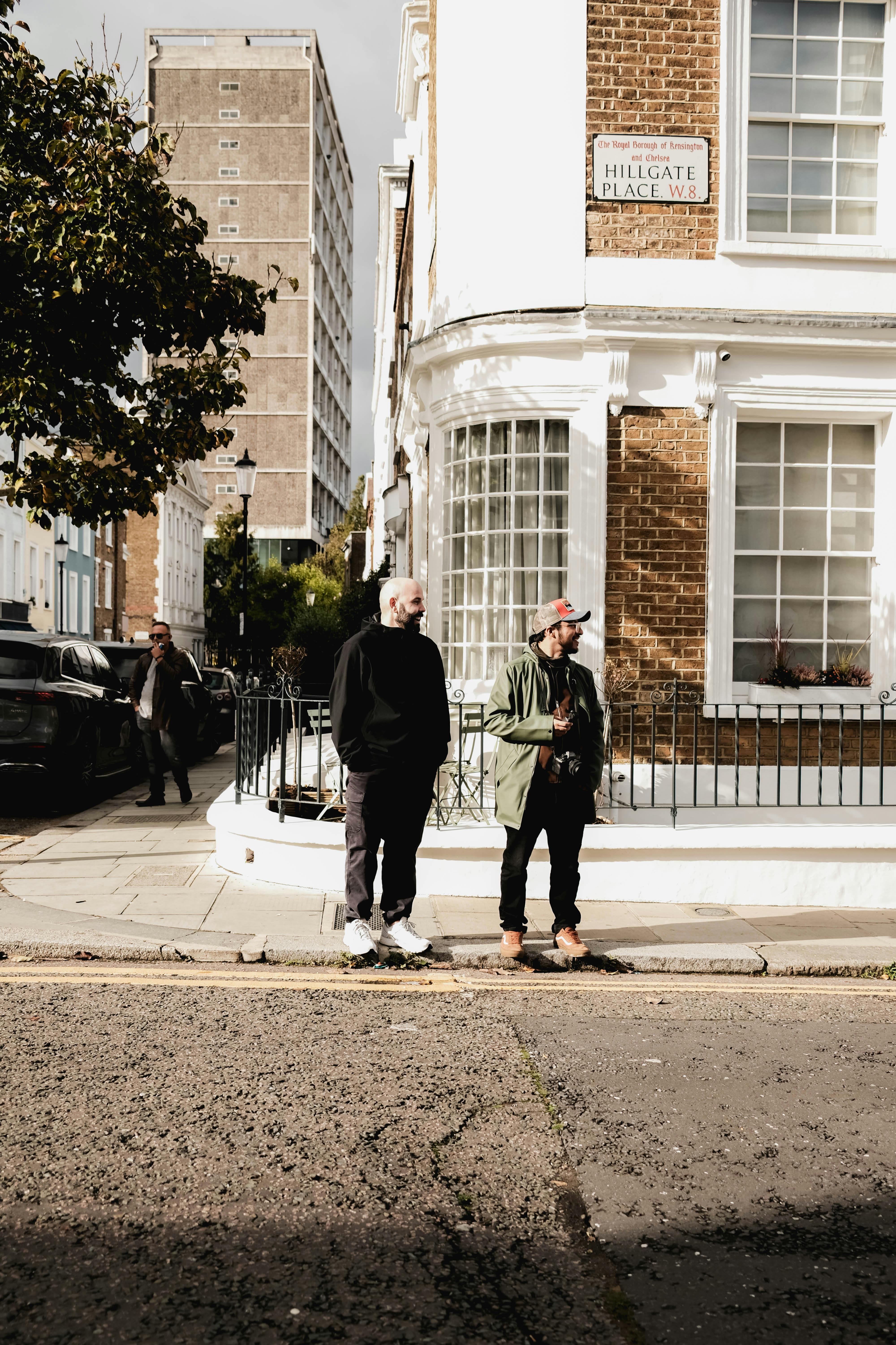 Two adults standing on the street outside Hillgate Place during daytime in an urban setting.