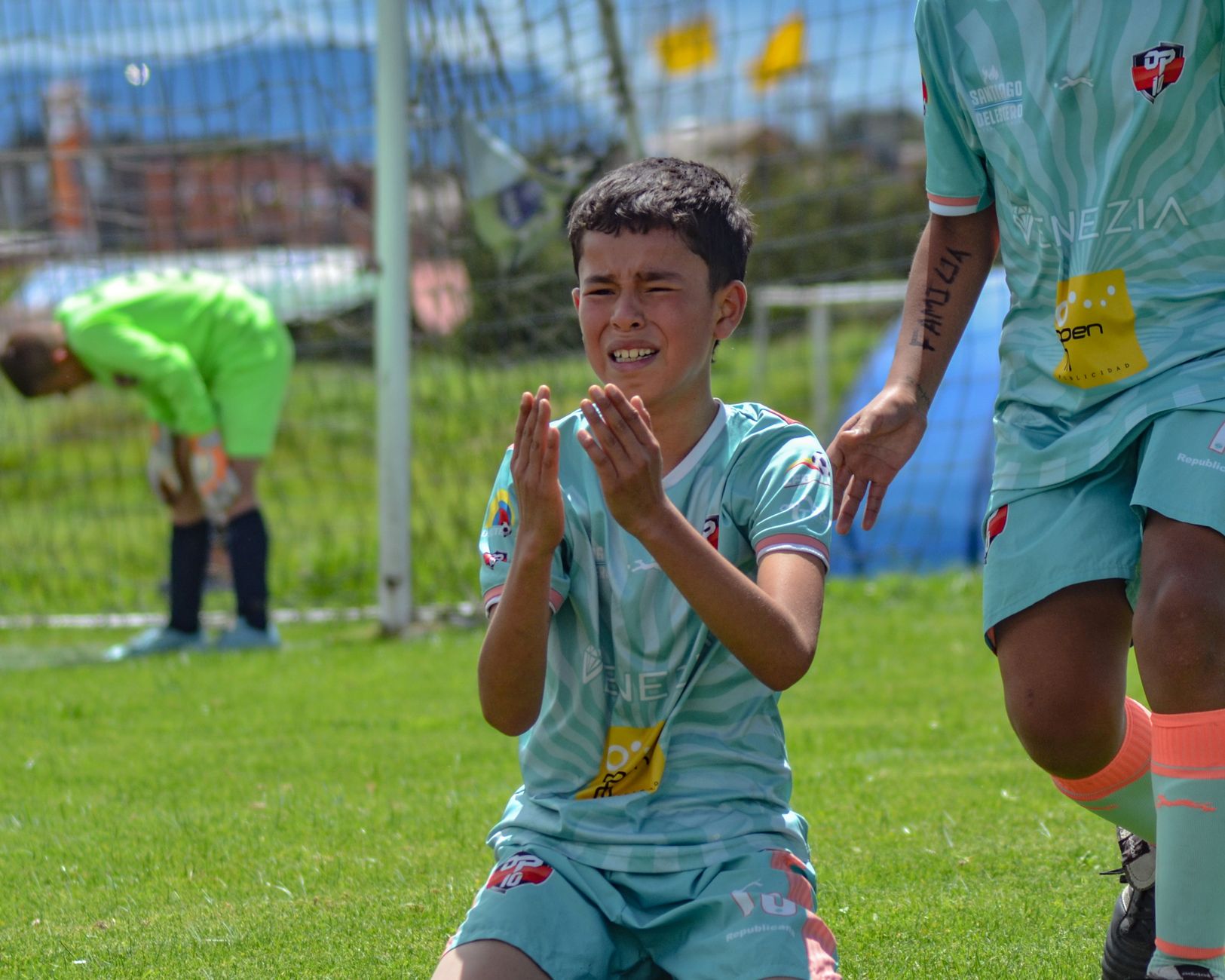 Young soccer player shows emotion after intense play on outdoor field.