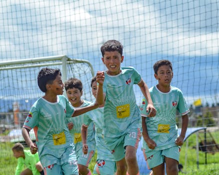 Energetic young soccer players celebrating a goal on a sunny day.
