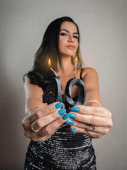 Woman holding black glittery candles shaped as 40, celebrating a milestone age.