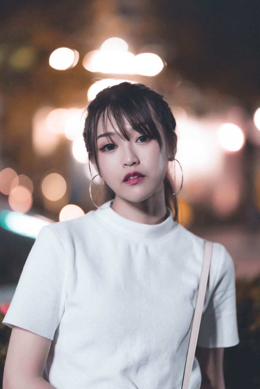 Elegant portrait of a young woman with bokeh lights, highlighting her modern fashion style and captivating gaze.