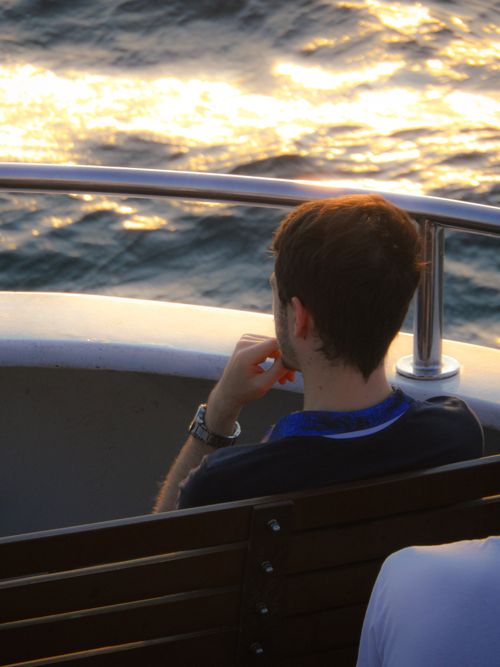 Free Young man enjoying a serene boat ride on a calm evening during sunset. Stock Photo