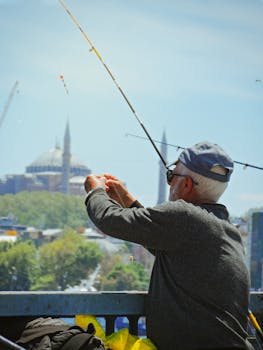 Senior man fishing on a sunny day in Istanbul with the skyline in the background.