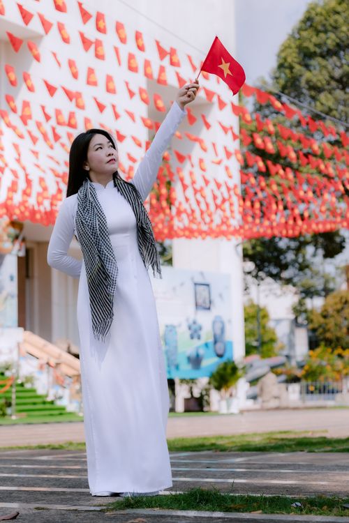 Free A woman in traditional attire celebrates outdoors with the Vietnamese flag. Stock Photo